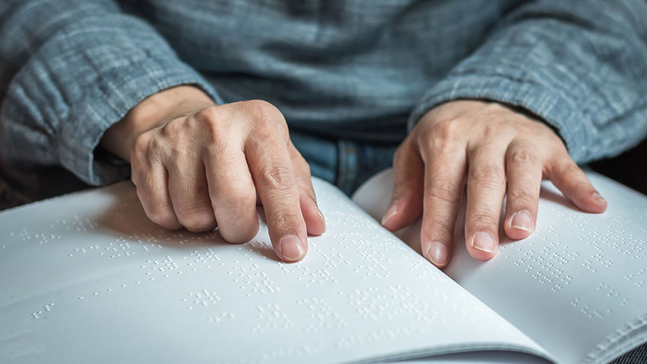 Pessoa cega lendo livro em Braille