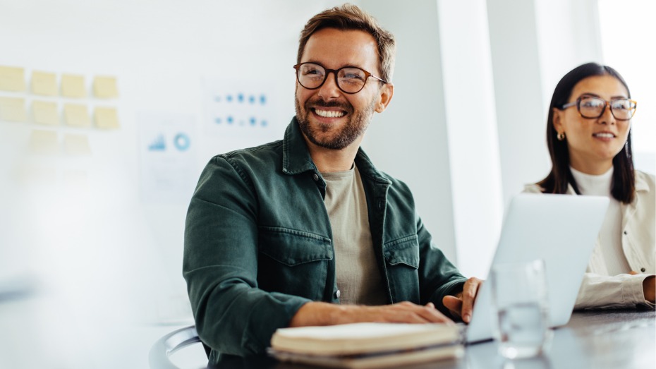 Foto de dois recrutadores sorrindo com um notebook na frente deles.