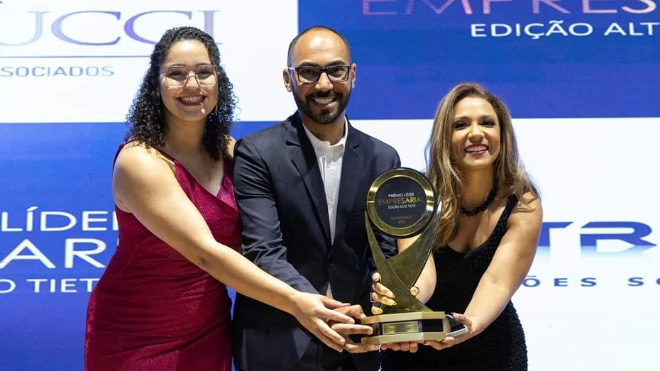 Imagem de três pessoas segurando um troféu.