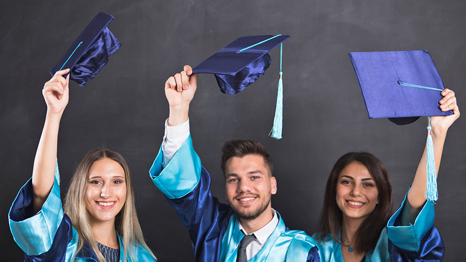Grupo de graduados que jogam tampões da graduação no ar