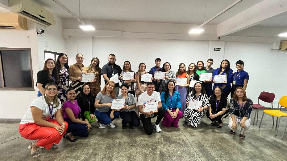 Foto com um grupo de pessoas sorrindo e olhando para frente. Alguns deles estão segurando um certificado de gratidão pela parceria com o CIEE.